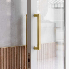 Zanda Duke 330mm Pull Handle in Satin Gold on white glass door with terracotta tiles